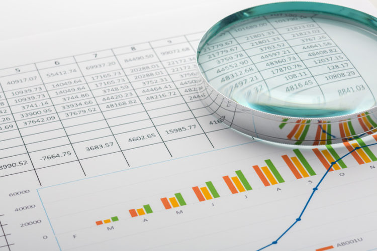 Close up of finance business sheet with magnifying glass