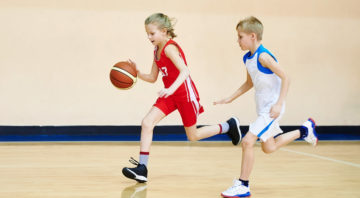 Girl and boy athlete in sport uniform playing basketball