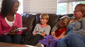 Social Worker Talking To Mother And Children At Home