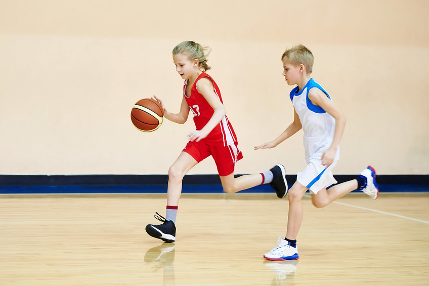 Girl and boy athlete in sport uniform playing basketball